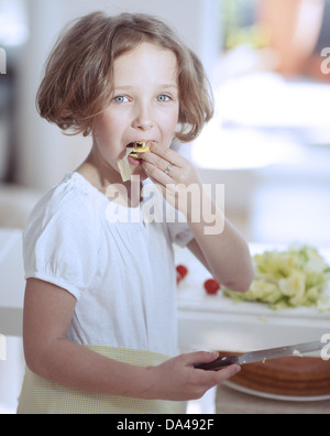 Junges Mädchen essen Salat, Messer in der Küche festhalten Stockfoto