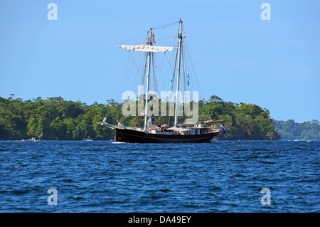 Schönes Segelschiff mit einer tropischen Insel im Hintergrund, Bocas del Toro, Panama Stockfoto