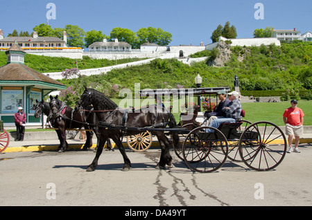 Michigan, Mackinac Island, Main Street (aka Huron). Traditionelle Pferd Buggy von schwarzes Pferd, Fort in Ferne gezogen. Stockfoto