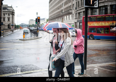 Zwei Mädchen gehen unter Union Jack Dach Regen Stockfoto