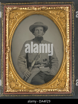 Dieses Foto aus der Library of Congress zeigt einen nicht identifizierten Soldaten in einer Konföderierten Uniform, ausgestattet mit einem Schwert und zwei Kanonen, was die Zeit des Amerikanischen Bürgerkriegs widerspiegelt. Stockfoto
