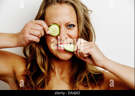 Eine junge Frau mit Gurke Stück über ihre Augen Stockfoto