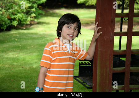 Porträt der lächelnde Brünette Junge stützte sich auf Zaun im Garten Stockfoto