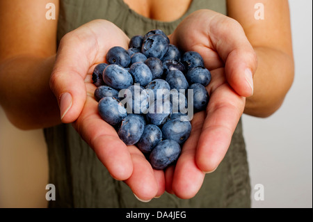 Eine junge Frau hält eine Handvoll Blaubeeren Stockfoto