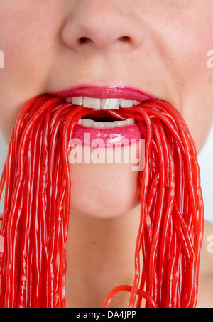 Eine Nahaufnahme von einer Frau Mund essen viel rote Lakritze Spitze Süßigkeiten Stockfoto