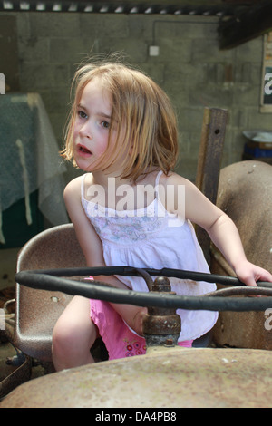 Junges Mädchen vorgibt, einen alten Traktor fahren Stockfoto