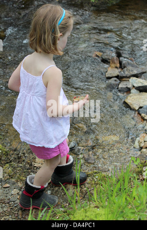 Junge Mädchen tragen Kiesel am Fluss Stockfoto