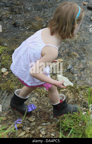 Junges Mädchen mit Steinen an einem Bach Stockfoto
