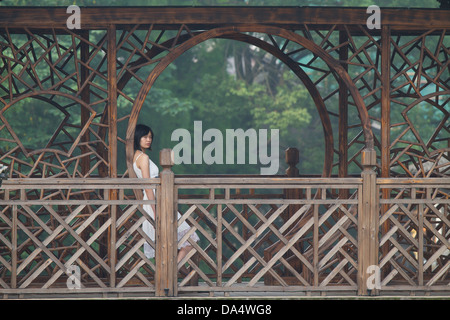 China, Wuzhen Xizha Scenic Zone, Frau sitzen auf historische alte Holzbrücke. Stockfoto