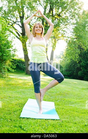 Frauen Fitness-Trainer tun Yoga Baum oder Vrksasana Pose im grünen park Stockfoto