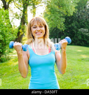 Porträt von weiblichen Fitness-Instruktor Training mit kleinen Gewichten im grünen park Stockfoto