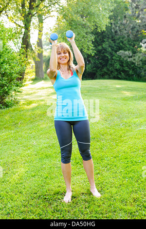 Frauen Fitness-Instruktor Training mit kleinen Gewichten im grünen park Stockfoto