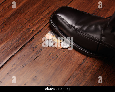 Suche nach Geld-Konzept eines Mann-Schuhs auf Änderung Münzen auf den Boden treten. Stockfoto