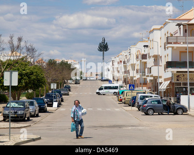 Straßenszene in Cabanas de Tavira, Algarve, Portugal mit Mann tragen Lebensmittel und Handy-Antenne als Baum verkleidet. Stockfoto