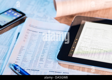 Aktienkurse in der Zeitung und auf dem Bildschirm eines Tablet-Computers. Stockfoto