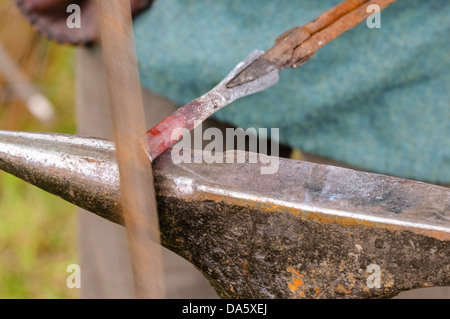 Ein Schmied verwendet eine Datei, ein Stück glühendes Eisen zu gestalten Stockfoto