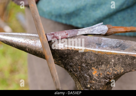 Ein Schmied verwendet eine Datei, ein Stück glühendes Eisen zu gestalten Stockfoto