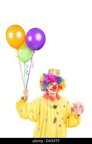 Männlichen Clown Kostüm hält jede Menge Luftballons und Popcorn-Box isoliert auf weißem Hintergrund Stockfoto