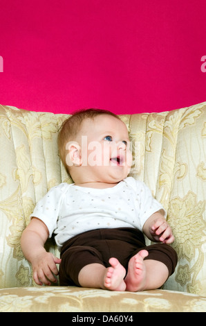 Baby Boy auf dem Stuhl sitzt und auf der Suche Stockfoto