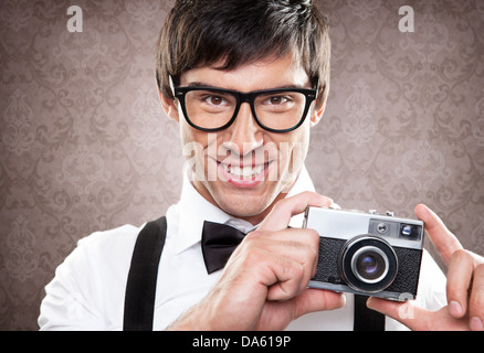 Ein hübscher junger Mann hält eine alte Kamera und lächelnd. Stockfoto