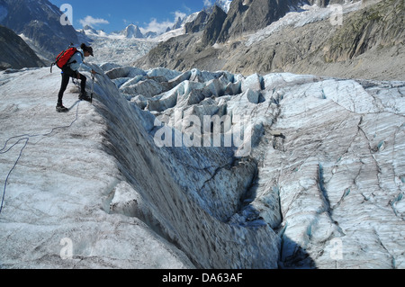 Frau Alpinist befestigt an einem Seil am Rande eine riesige Gletscherspalte in einem Eisfall in das "Meer aus Eis", liefen aus dem mont Stockfoto