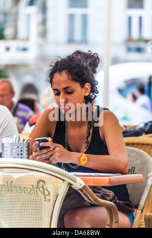 Eine attraktive junge Frau nutzt ihr iPhone sitzen in einem Straßencafé am Altstädter Ring, Prag Stockfoto