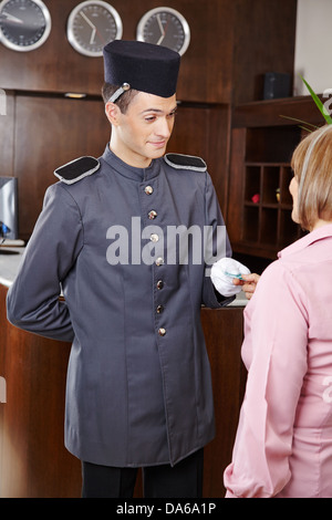 Freundlichen Mitarbeiter der Rezeption im Hotel senior Frau Schlüsselkarte verleihen Stockfoto