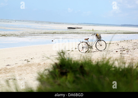 Eine verlassene Fahrrad geparkt auf einem weißen Sandstrand Paradies in Sansibar mit blauem Wasser Stockfoto