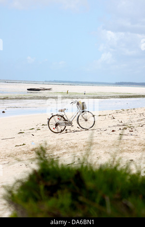 Eine verlassene Fahrrad geparkt auf einem weißen Sandstrand Paradies in Sansibar mit blauem Wasser Stockfoto