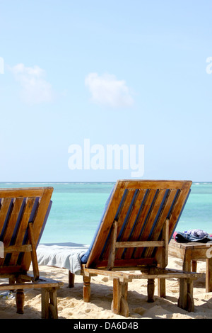Eine perspektivische Ansicht von einem weißen Sandstrand Paradies in Sansibar mit Smaragd blauen, klaren Wasser und einem blauen Himmel und zwei hölzerne chai Stockfoto