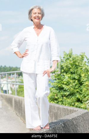Lächelnd und aktiven senior Frau im weißen Kleid Stockfoto