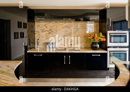 Blasse Marmor Splash-Rücken und Arbeitsplatte auf schwarzen ausgestattete Einheit in modernen Küche mit gebogenen Mittelinsel Einheit Stockfoto