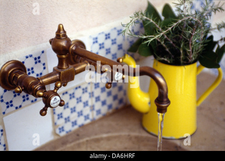 Altmodische Messing Wasserhahn passend über Waschbecken mit Zweige frischer Kräuter in alte Emaille Kaffee Topf weiter sinken Stockfoto