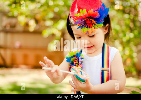 Kleine Asiatin in einem Clown-Outfit und mit einem Lolly Pop spielen Stockfoto