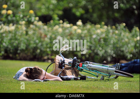 Cardiff, UK. 5. Juli 2013. Heißes Wetter in Cardiff. Eine junge Frau sonnt sich neben ihr Fahrrad im Cathays Park. Bildnachweis: Polly Thomas / Alamy Live News Stockfoto