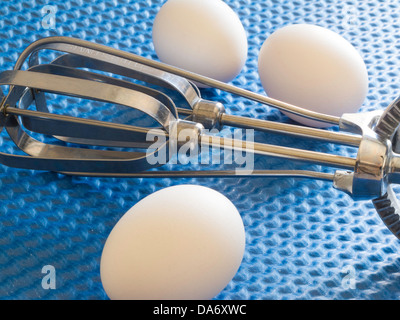 Drei Eiern mit Vintage Rotary Hand Schlägel auf blauem Hintergrund Stockfoto