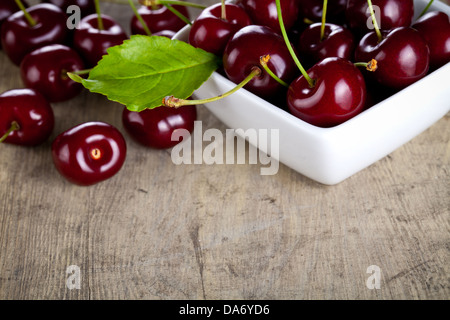 Kirschen in Schüssel auf Holztisch Hintergrund weiß. Kopieren Sie Raum. Makroaufnahme Stockfoto