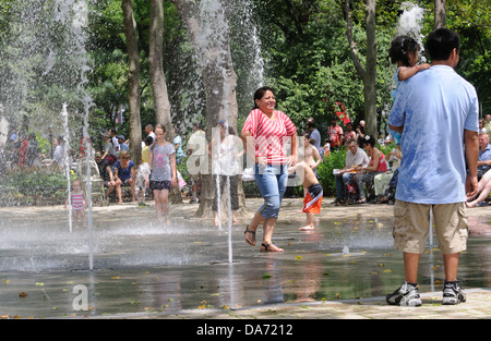 Auf einer heißen, feuchten Juli 4 Erwachsene und Kinder abgekühlt in einem Brunnen im Battery Park in lower Manhattan. Stockfoto