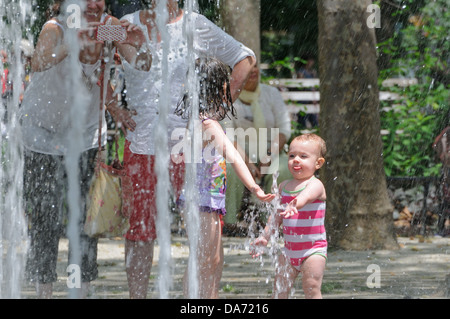 Auf einer heißen, feuchten Juli 4 Erwachsene und Kinder abgekühlt in den Brunnen im Battery Park in Manhattan. Stockfoto