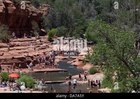 9. Juni 2013 - Sedona, Arizona, USA - Besucher genießen das kühle Wasser von einem überfüllten Slide Rock State Park in Sedona. Sedona Hauptattraktion ist eine Reihe von roten Sandstein-Formationen, die zu glühen in leuchtende Orange und rot, wenn der Aszendent oder untergehende Sonne beleuchtet erscheinen. Die roten Felsen bilden eine beliebte Kulisse für zahlreiche outdoor-Aktivitäten von spirituellen Bestrebungen bis hin zu den Hunderten von Wander- und Mountainbike-Strecken. Sedona war benannt nach Sedona Arabelle Miller Schnebly (1877âˆ "1950), die Ehefrau von Theodore Carlton Schnebly, die Stadt erste Postmeister. (Bild Kredit: Â © Ruaridh Eintopf Stockfoto