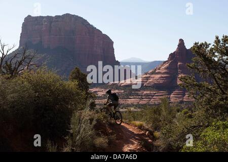 9. Juni 2013 - Sedona, Arizona, USA - Fahrradtouren Mountainbiker seine auf roten Slickrock unten hoch aufragende Kuppen auf dem HiLine Trail in Sedona. Sedona Hauptattraktion ist eine Reihe von roten Sandstein-Formationen, die zu glühen in leuchtende Orange und rot, wenn der Aszendent oder untergehende Sonne beleuchtet erscheinen. Die roten Felsen bilden eine beliebte Kulisse für zahlreiche outdoor-Aktivitäten von spirituellen Bestrebungen bis hin zu den Hunderten von Wander- und Mountainbike-Strecken. Sedona war benannt nach Sedona Arabelle Miller Schnebly (1877âˆ "1950), die Ehefrau von Theodore Carlton Schnebly, die Stadt erste Postmeister. (Cred Stockfoto