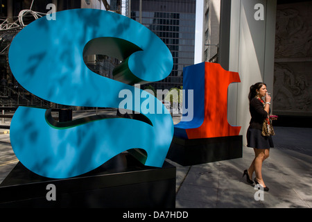 Eine Frau raucht eine Zigarette durch eine große rote Nummer eins und zwei, eine Kunstinstallation Teil mit dem Titel "One Through Zero (die zehn Zahlen)" von amerikanischen pop-Künstler Robert Indiana (b. 1928), in Lime Street, City of London, der Hauptstadt Quadratmeile und seine finanzielle Herz. Stockfoto