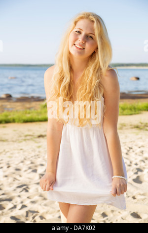 Lächelnde Frau in weißem Kleid mit goldenen Haaren Stockfoto