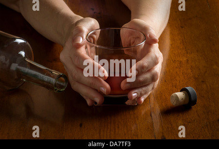 Konzept-Foto-Closeup für Alkoholismus Krankheit zeigt Hände Whiskeyglas und leere Flasche Stockfoto