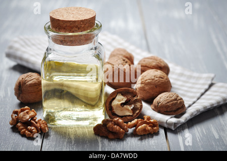 Walnussöl mit Nüssen auf einem hölzernen Hintergrund Stockfoto