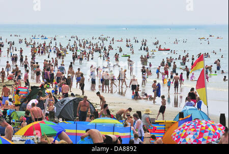 West Wittering, West Sussex, UK. 7. Juli 2013. Sizzling Sonntag als Tagesausflügler an den beliebten West Wittering Strand nehmen um sich abzukühlen, als die Temperaturen auf 30 Grad im Landesinneren in Südengland 2. Parkplatz geöffnet um bis zu 10,000 Autos. iPhone iPad waren bereit, die Wimbledon Tennis, unter Strandzelte und unter Sonnenschirmen zu streamen Stockfoto