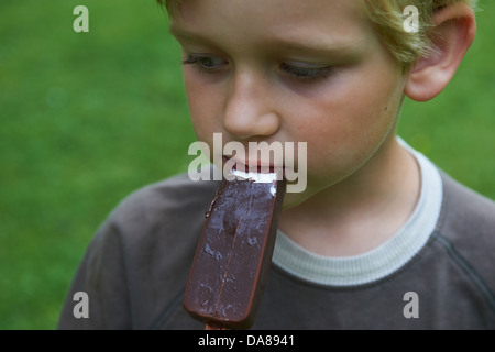 Blondes Kind 6-8 jährige junge hält und essen Eis im Sommer Stockfoto