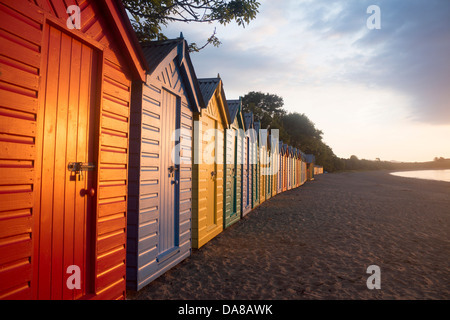 Bunt bunt bemalten Strandhütten im Morgengrauen / Sonnenaufgang Llanbedrog Strand Llyn Halbinsel Gwynedd North Wales UK Stockfoto