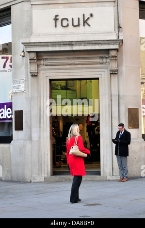 Eine Frau trägt einen roten Mantel geht es vorbei an French Connection-Shop. Regent Street, London. Stockfoto