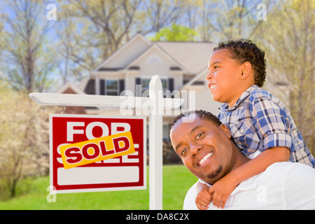 Glücklich gemischte Rennen-Vater und Sohn vor verkauften Immobilien Zeichen und neues Haus. Stockfoto